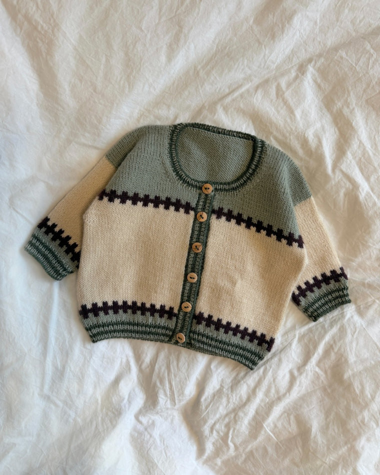 Cross Cardigan Junior og Cross Cardigan Baby liggende sammen på en stol