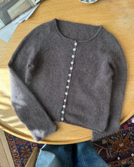Mørkelilla Ivy Cardigan liggende på sofabord