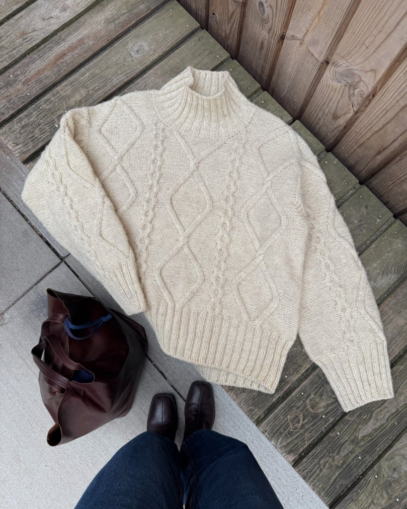 Hvid Saga Sweater liggende på bænk