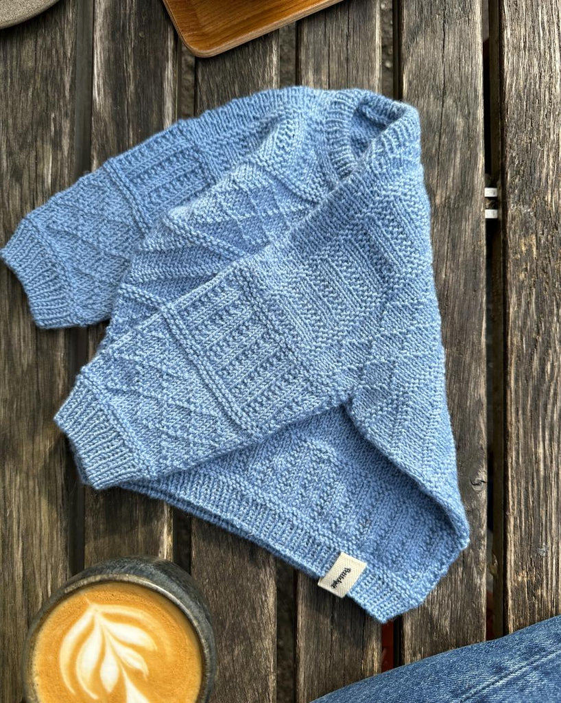 Lyseblå Storm Sweater Baby liggende på bænk