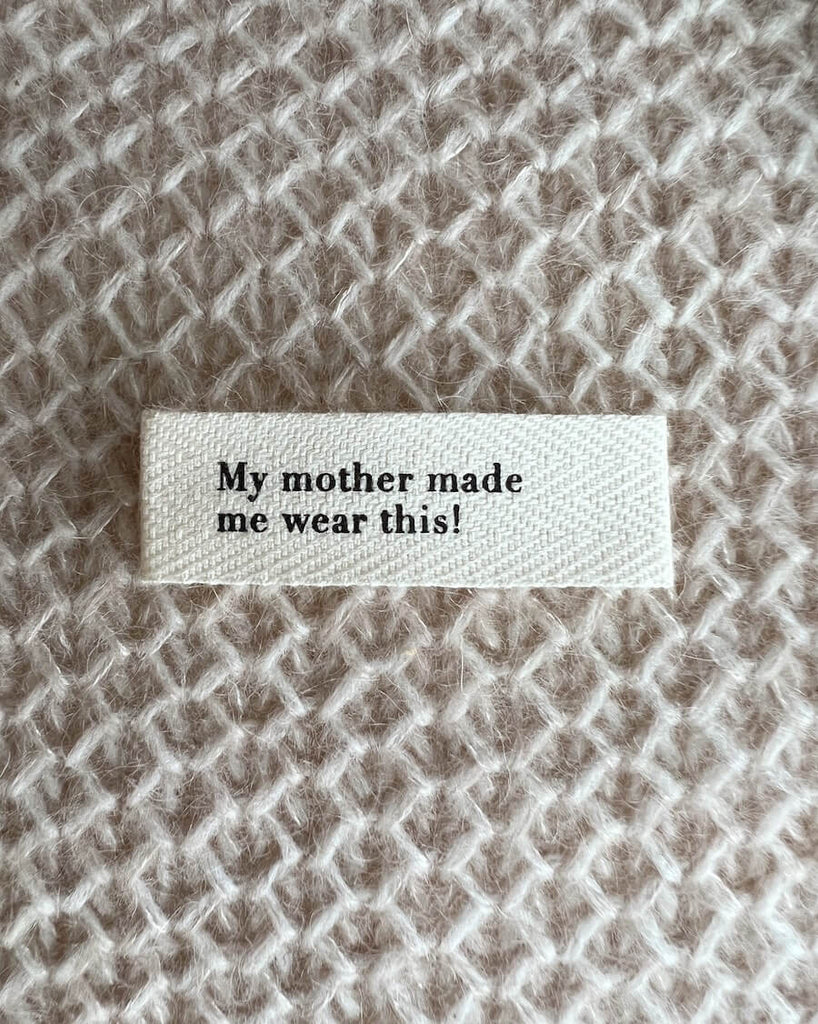 Petiteknit tekstillabel med teksten "My mother made me wear this!".