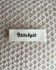énkelt Petiteknit label med sort tekst