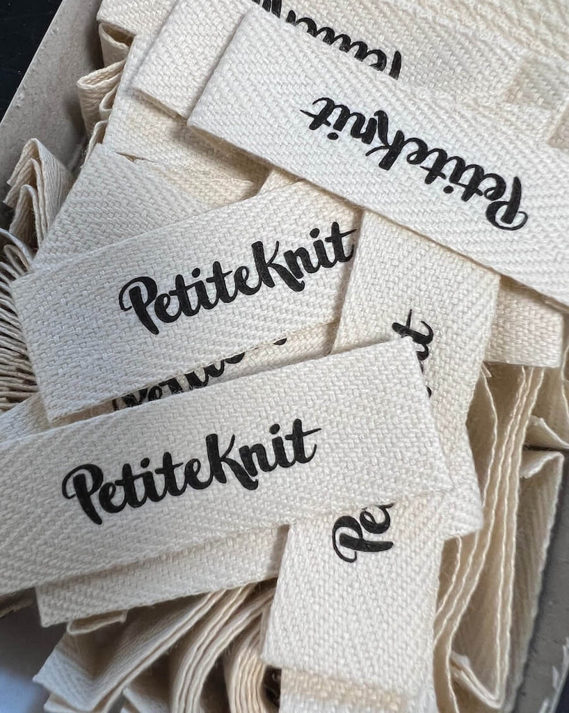 Nærbillede af  mange Petiteknit tekstil labels